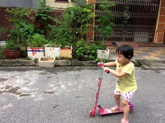 Trẻ thích thú đạp xe trượt scooter trước cửa nhà. Ảnh: Thanh Huyền